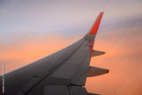 View on the sunset and airplane wing from the inside