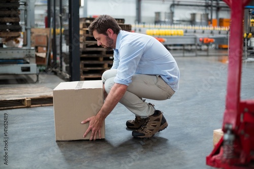 Factory worker picking up cardboard boxes in factory