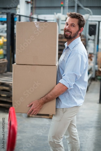 Factory worker carrying cardboard boxes in factory