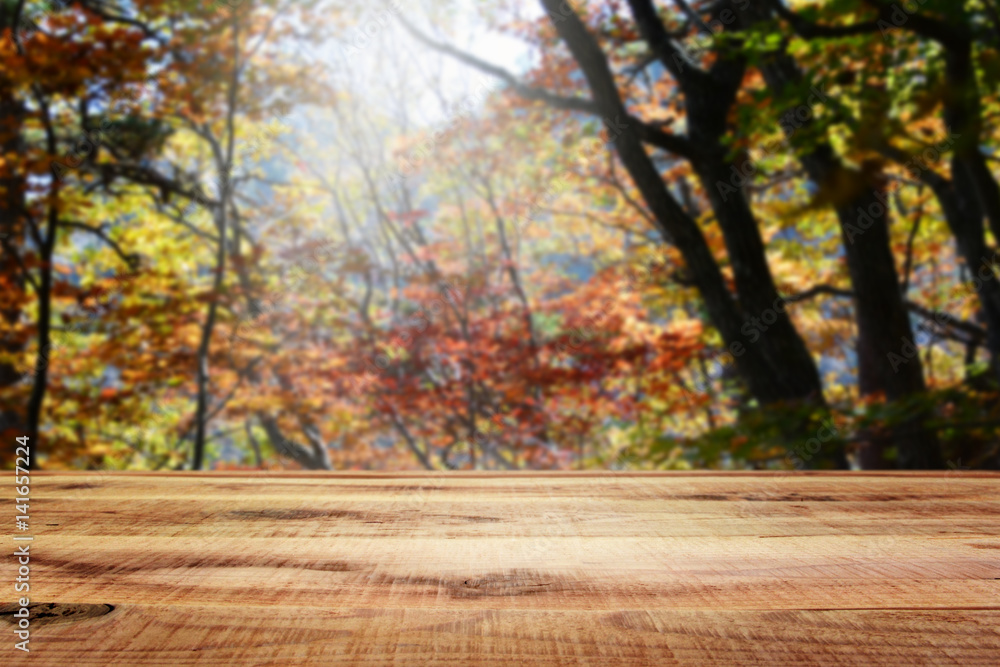 Wooden table and blur autumn background.