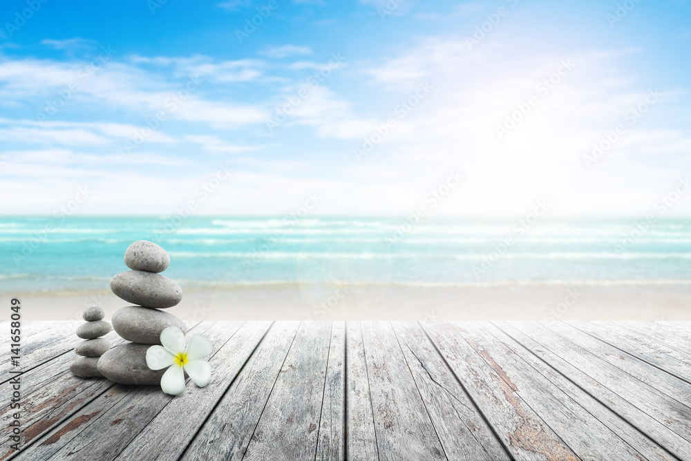 Stack of pebble stones and Plumeria at the beach on a wooden surface. Concept Zen, Spa, Summer, Beach, Sea, Relax. - obrazy, fototapety, plakaty 