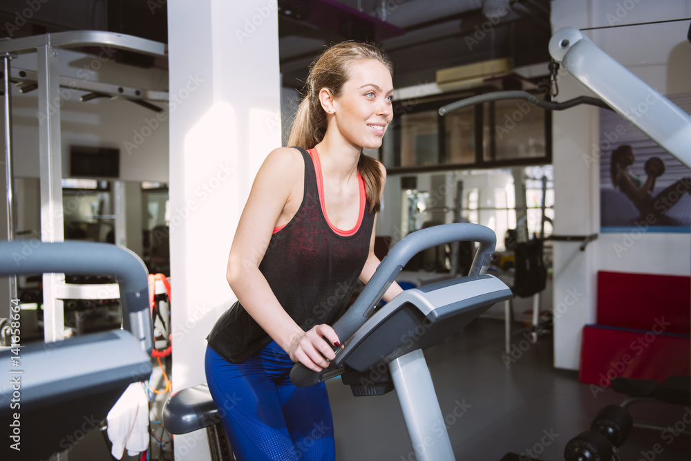 Smiling woman riding an exercise bike in gym Smiling woman riding an exercise bike in gym