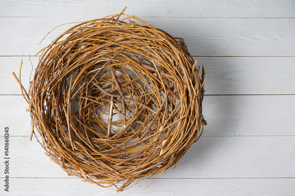 Top view of empty wicker nest over white wooden planks Top view of empty wicker nest over white wooden planks