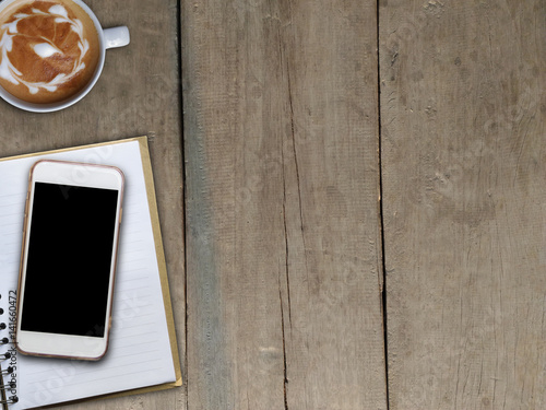 Smart phone on book and hot coffee art on wooden board photo