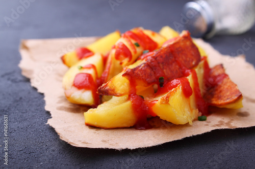 Baked potatoes with ketchup on a white background