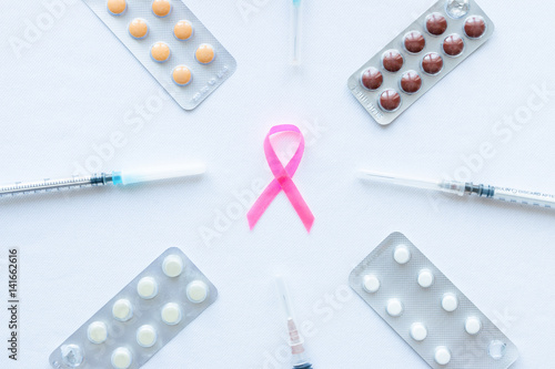 pink ribbon symbol for breast cancer on a white background with syringes and tablets