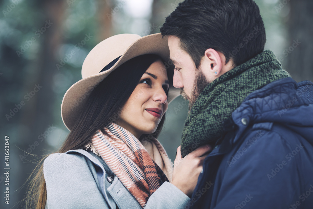 Close-up of romantic couple looking at each other in forest during winter Close-up of romantic couple looking at each other in forest during winter