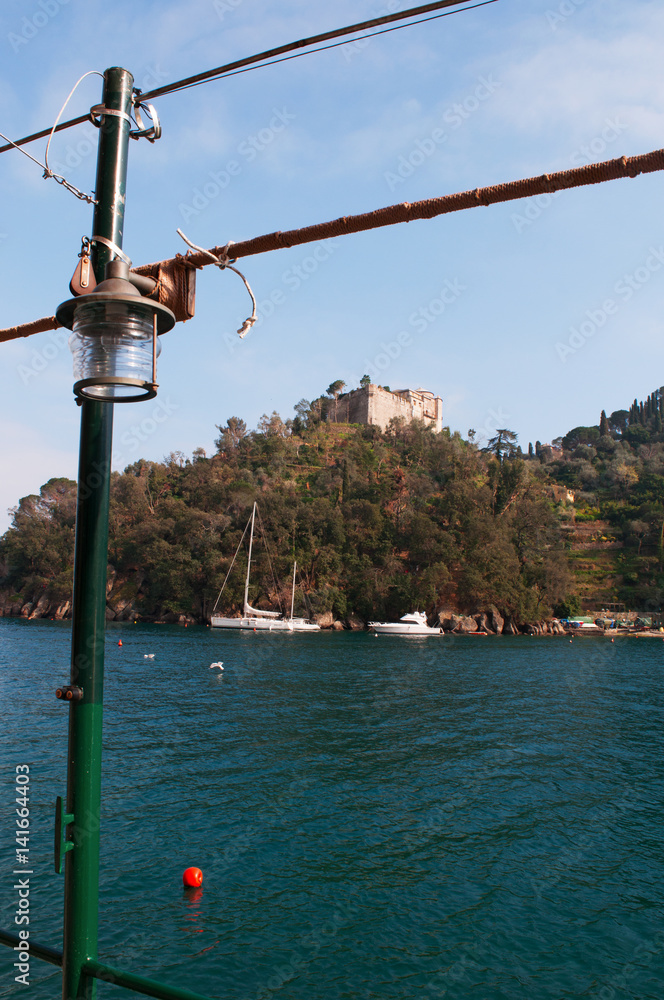 Italia, 16/03/2017: le barche al porto con vista sul Castello Brown, noto come Castello di San Giorgio, residenza difensiva e nobile sulla collina che domina la baia di Portofino