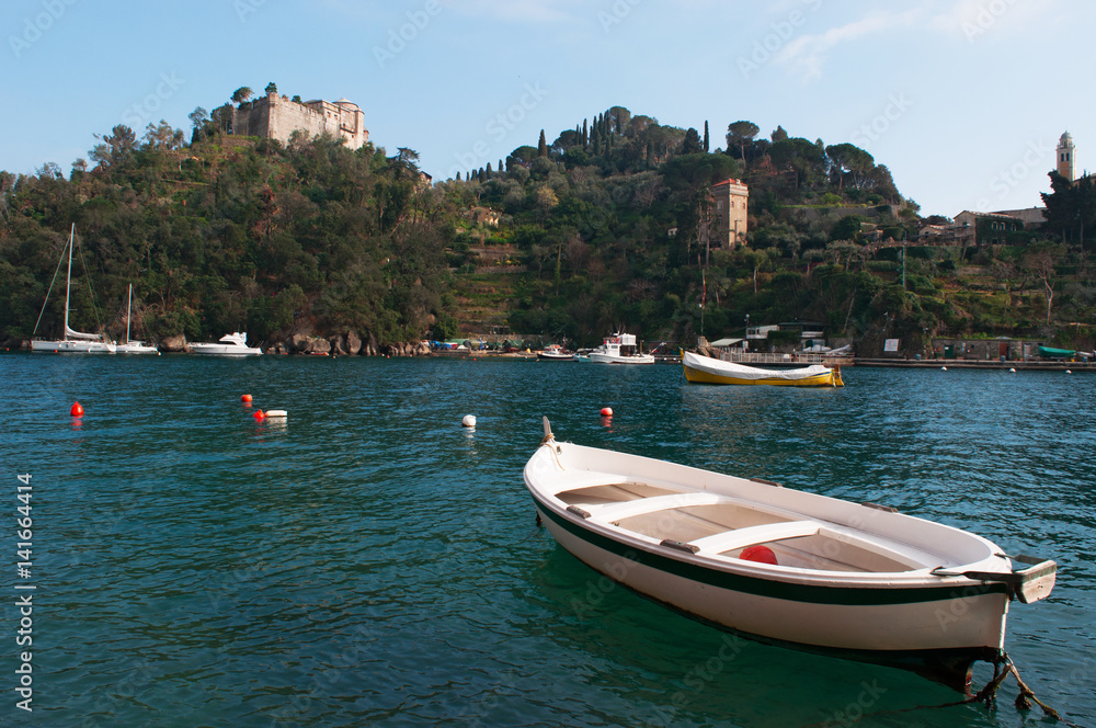 Italia, 16/03/2017: le barche al porto con vista sul Castello Brown, noto come Castello di San Giorgio, residenza difensiva e nobile sulla collina che domina la baia di Portofino