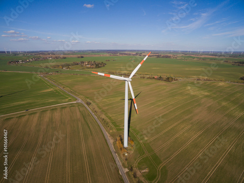 aerial view of a wind turbine in agriculture fields with blue sky