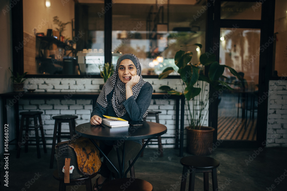 Portrait of smiling woman with books sitting in cafe Portrait of smiling woman with books sitting in cafe