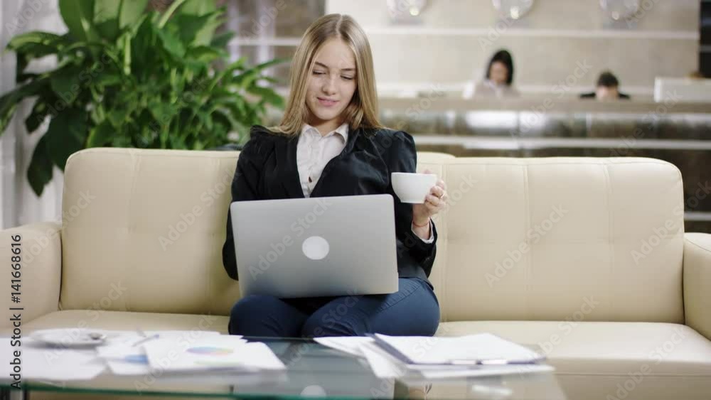 happy woman tourist typing on laptop in the hotel lobby happy woman tourist typing on laptop in the hotel lobby