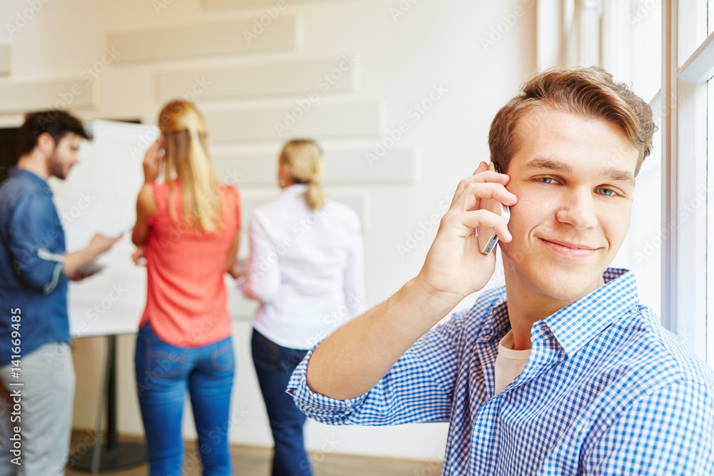 Junger Mann als Student telefoniert mit Handy Junger Mann als Student telefoniert mit Handy