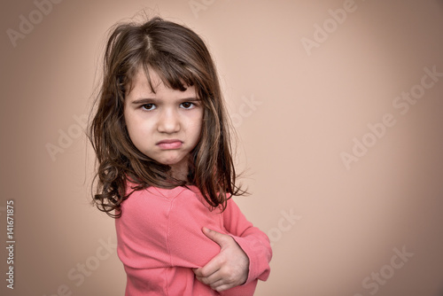 Angry and pouting cute young girl with crossed arms