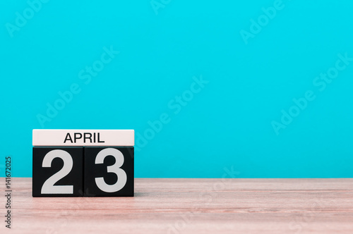April 23rd. Day 23 of month, calendar on wooden table and turquoise background. Spring time, empty space for text