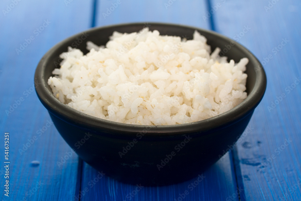 boiled rice in black bowl in wooden background boiled rice in black bowl in wooden background