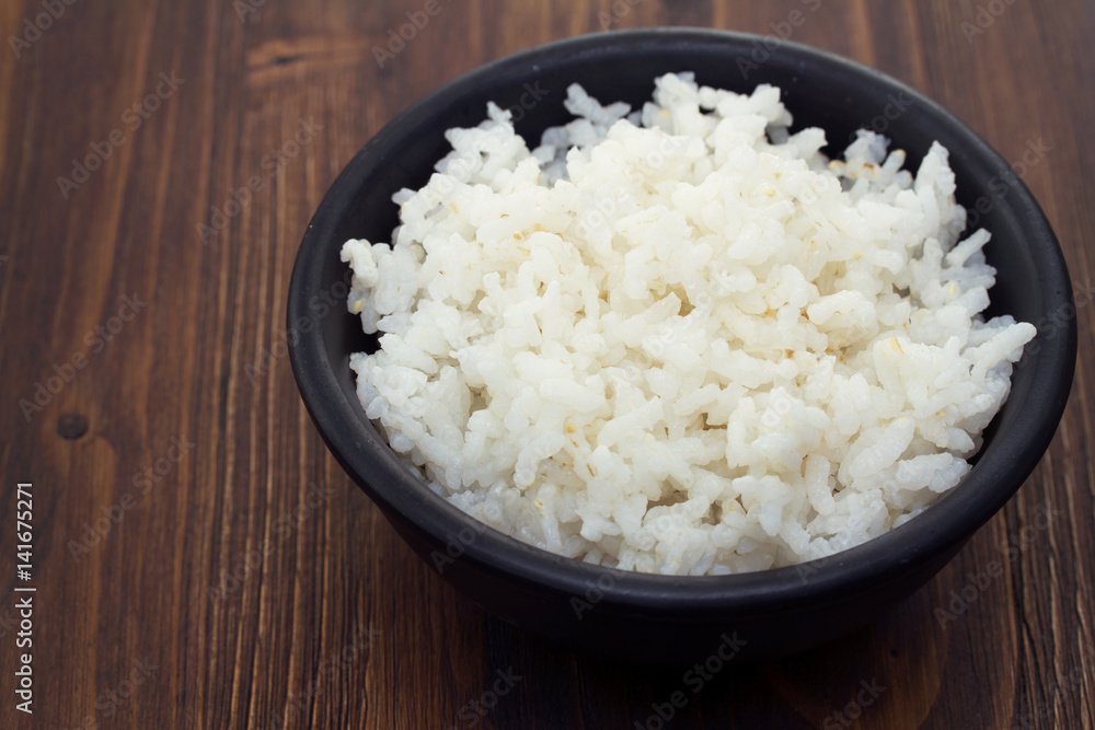 boiled rice in black bowl in wooden background boiled rice in black bowl in wooden background
