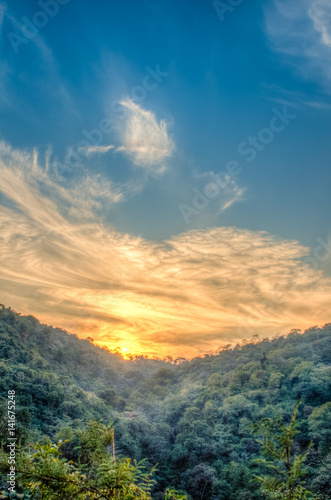 Mountain forest landscape under evening sky with clouds in sunlight. Majestic sunset in indian Himalaya mountains. HDR image
