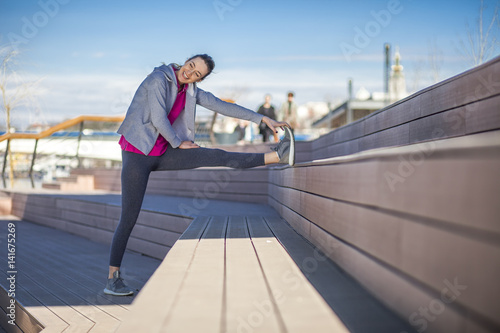 Morning exercise near the river. Young woman on recreation and jogging.  Warm up and stretch muscles before the morning exercise by the river © nikodash