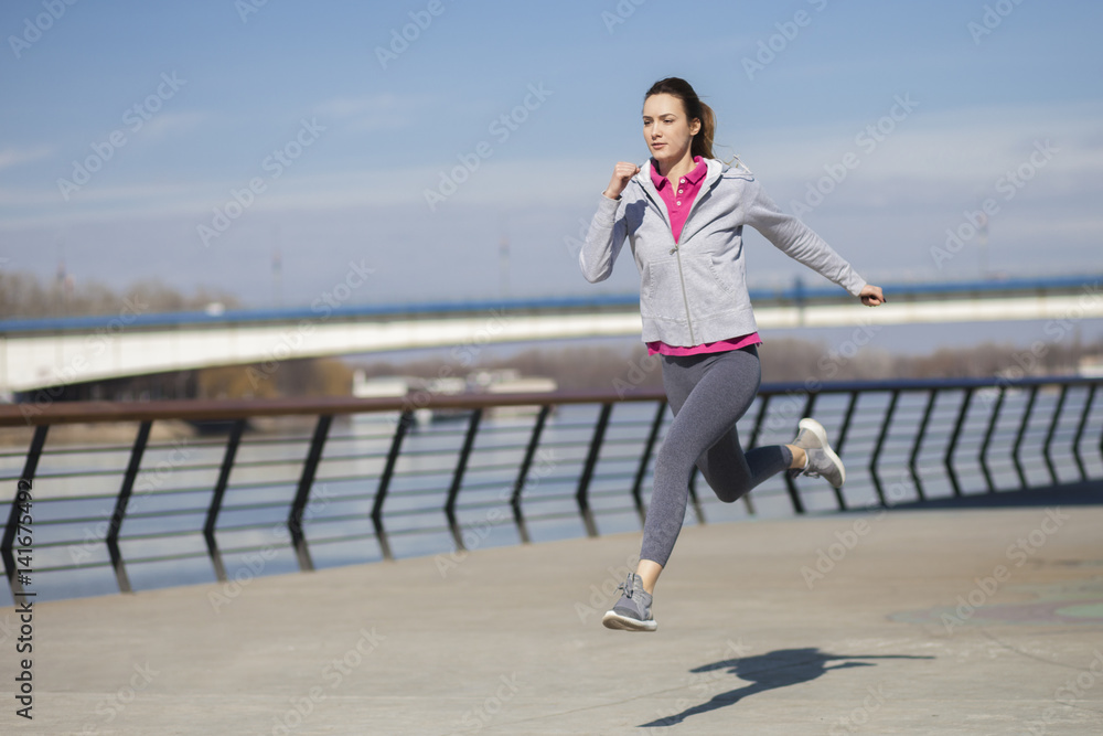 Morning exercise along the river. A young woman on recreation and jogging Morning exercise along the river. A young woman on recreation and jogging