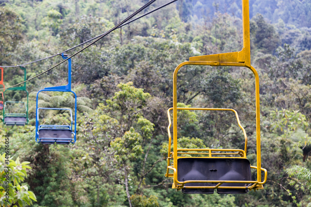 Yellow, blue, green and orange chairs on the ski lift at the Recinto del Pensamiento nature reserve near Manizales, Colombia. Yellow, blue, green and orange chairs on the ski lift at the Recinto del Pensamiento nature reserve near Manizales, Colombia.
