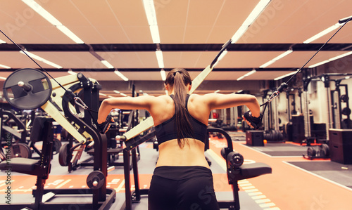 woman flexing muscles on cable machine in gym