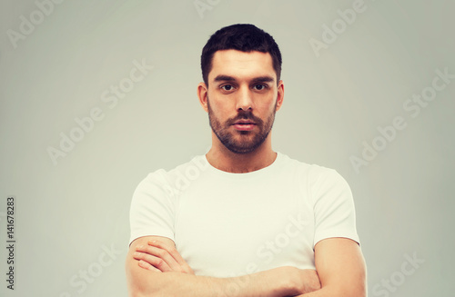 young man with crossed arms over gray background