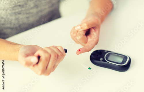 close up of woman making blood test by glucometer