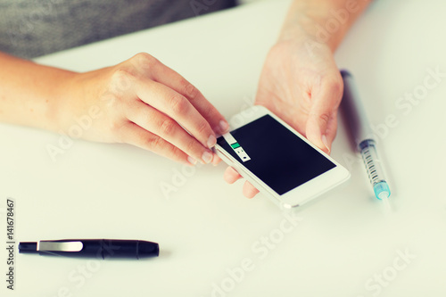 close up of woman with smartphone doing blood test
