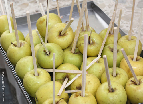 apples stuffed with wooden sticks ready to be cooked with carame photo