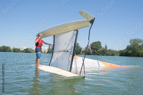 salior trying to right his catamaran after capsize photo