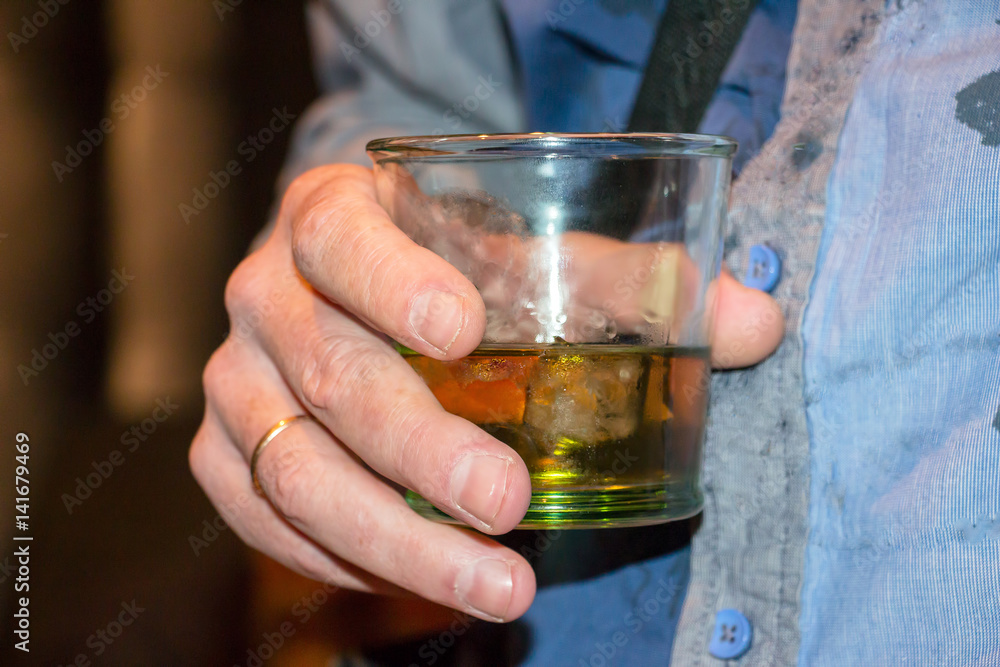 Man is holding a glass of scotch whiskey with ice Man is holding a glass of scotch whiskey with ice