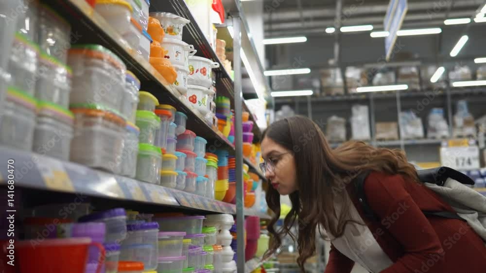 Young woman chooses a plastic lunch box in which the products remain fresh for a long time. She will put food and attributed it to work in this plastic boxes. Young woman chooses a plastic lunch box in which the products remain fresh for a long time. She will put food and attributed it to work in this plastic boxes.