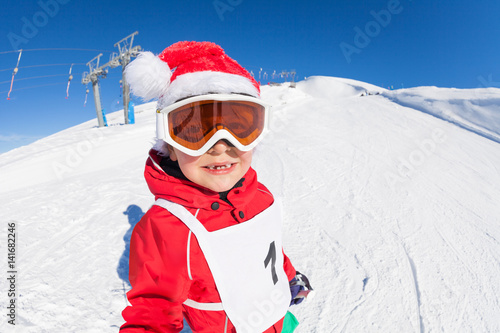 Cute skier in Santa's hat having fun at snowy hill