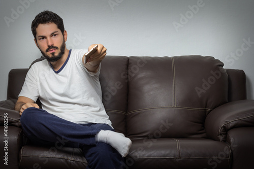 Serious man holding remote control and watching TV