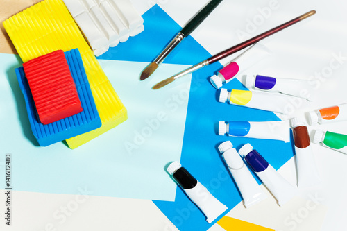 Brushes, tubes of paint and modeling clay on table