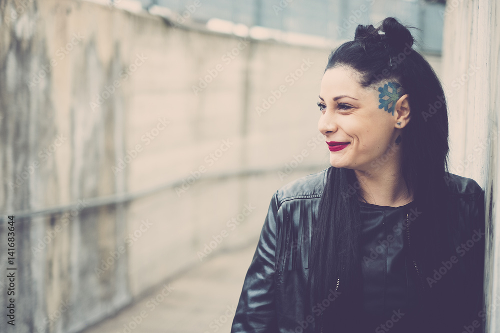 Smiling dark-haired young woman with black leather jacket and tattoos Smiling dark-haired young woman with black leather jacket and tattoos