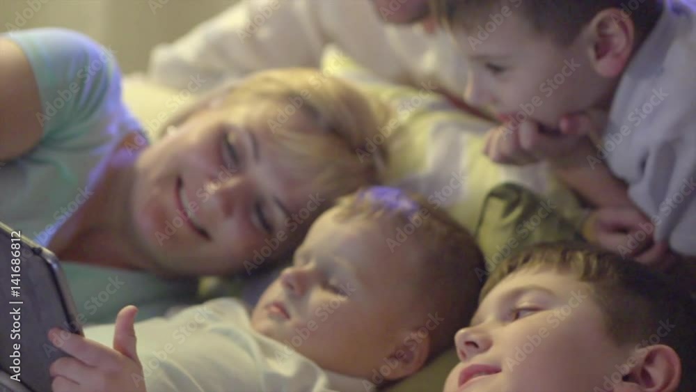 Happy family together watching movie on tablet computer in dark room. Slow motion 240 fps, UHD 4K video Happy family together watching movie on tablet computer in dark room. Slow motion 240 fps, UHD 4K video