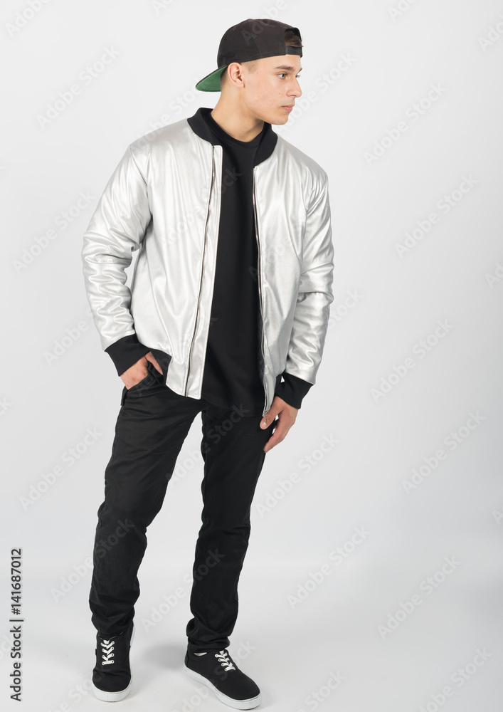 Young muscular man wearing black trousers, grey jacket, snapback and sneakers on white background Young muscular man wearing black trousers, grey jacket, snapback and sneakers on white background