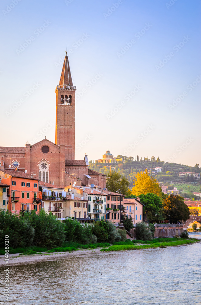 Beautiful old houses on Adige river and tower of Santa Anastasia church in Verona, Veneto region, Italy.