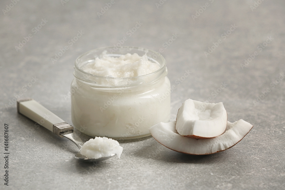 Fresh coconut oil in glassware and spoon on grey background Fresh coconut oil in glassware and spoon on grey background