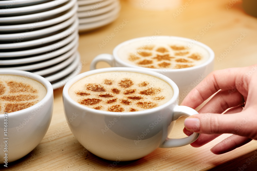 A lot of cups of coffee and a plate with a fire. Cappuccino coffee. A cup of latte, cappuccino or espresso coffee with milk. Drawing the foam milk on top. A lot of cups of coffee and a plate with a fire. Cappuccino coffee. A cup of latte, cappuccino or espresso coffee with milk. Drawing the foam milk on top.