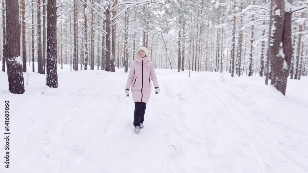 Nice girl in warm winter clothes walks through the forest in the winter in the daytime. Nice girl in warm winter clothes walks through the forest in the winter in the daytime.