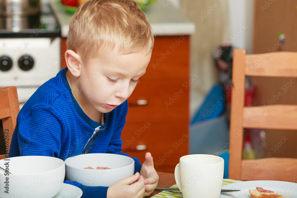 Kid boy eating breakfast, cereals and milk in bowl Kid boy eating breakfast, cereals and milk in bowl