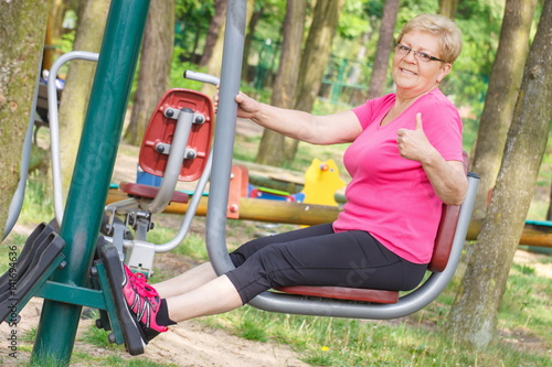 Senior woman exercising lower body on outdoor gym, healthy lifestyle