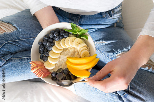 Eating healthy breakfast bowl porridge oats cooked granola fresh and dry fruits and honey in blue ceramic bowl clean eating, dieting, detox, vegetarian food concept