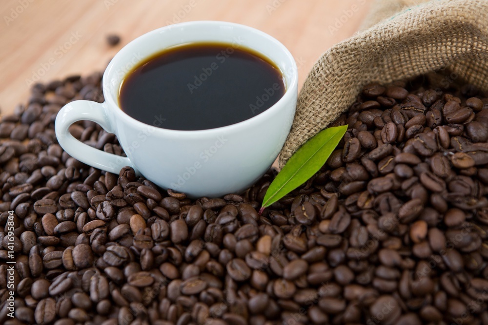 Fototapeta premium Coffee cup with coffee beans and coffee leaf