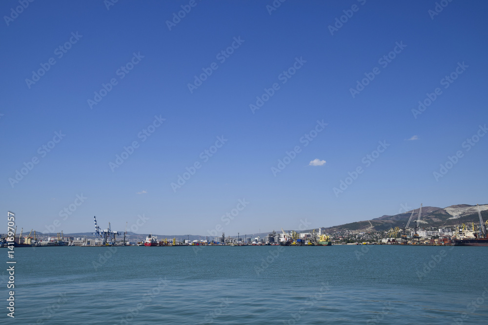 Cargo port with port cranes. Sea bay and mountainous coast.