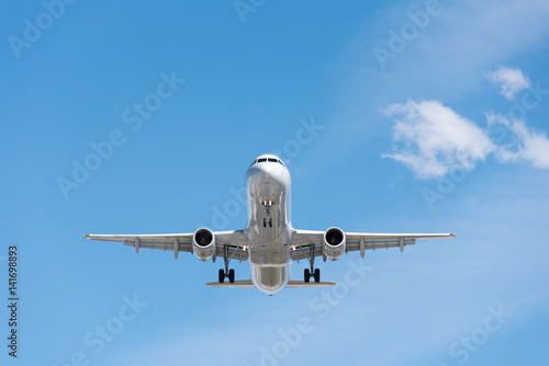Commercial airplane flying in blue sky, full flap and landing gear extended