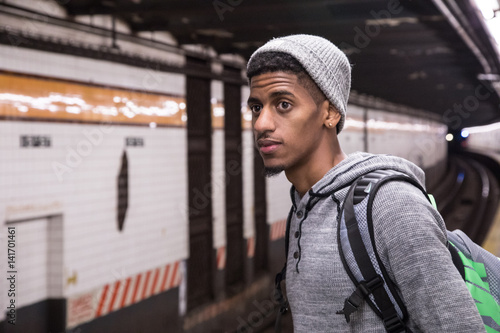 A young, black male waits for a NYC subway train